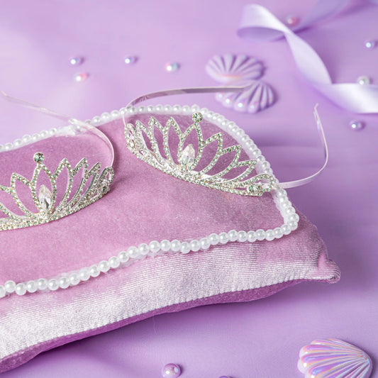 Silver tiara with pearls on a purple pillow with decorative elements