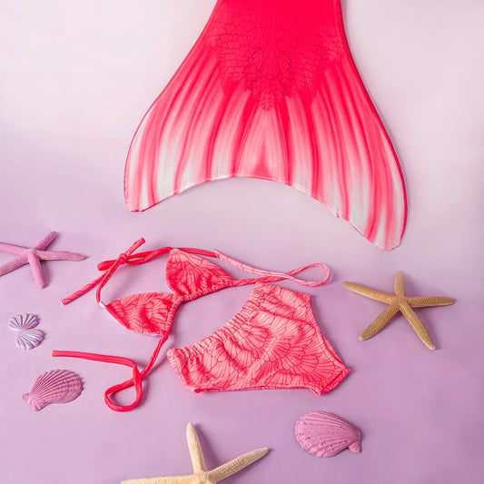 Pink mermaid tail and bikini set with starfish and shells on a pink background