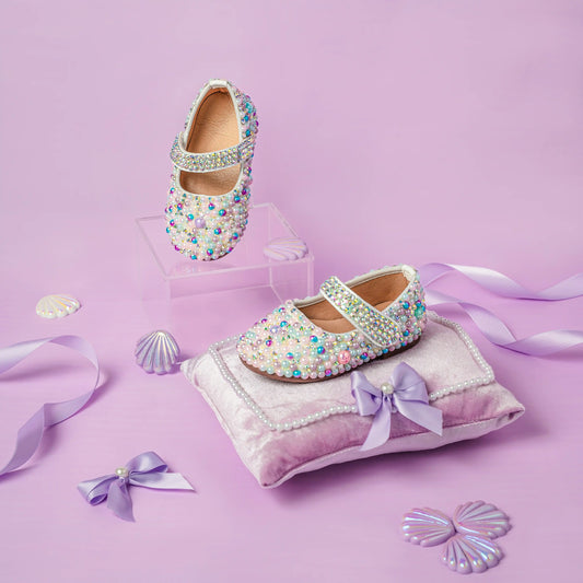 Decorative children's shoes with colorful embellishments on a pink background