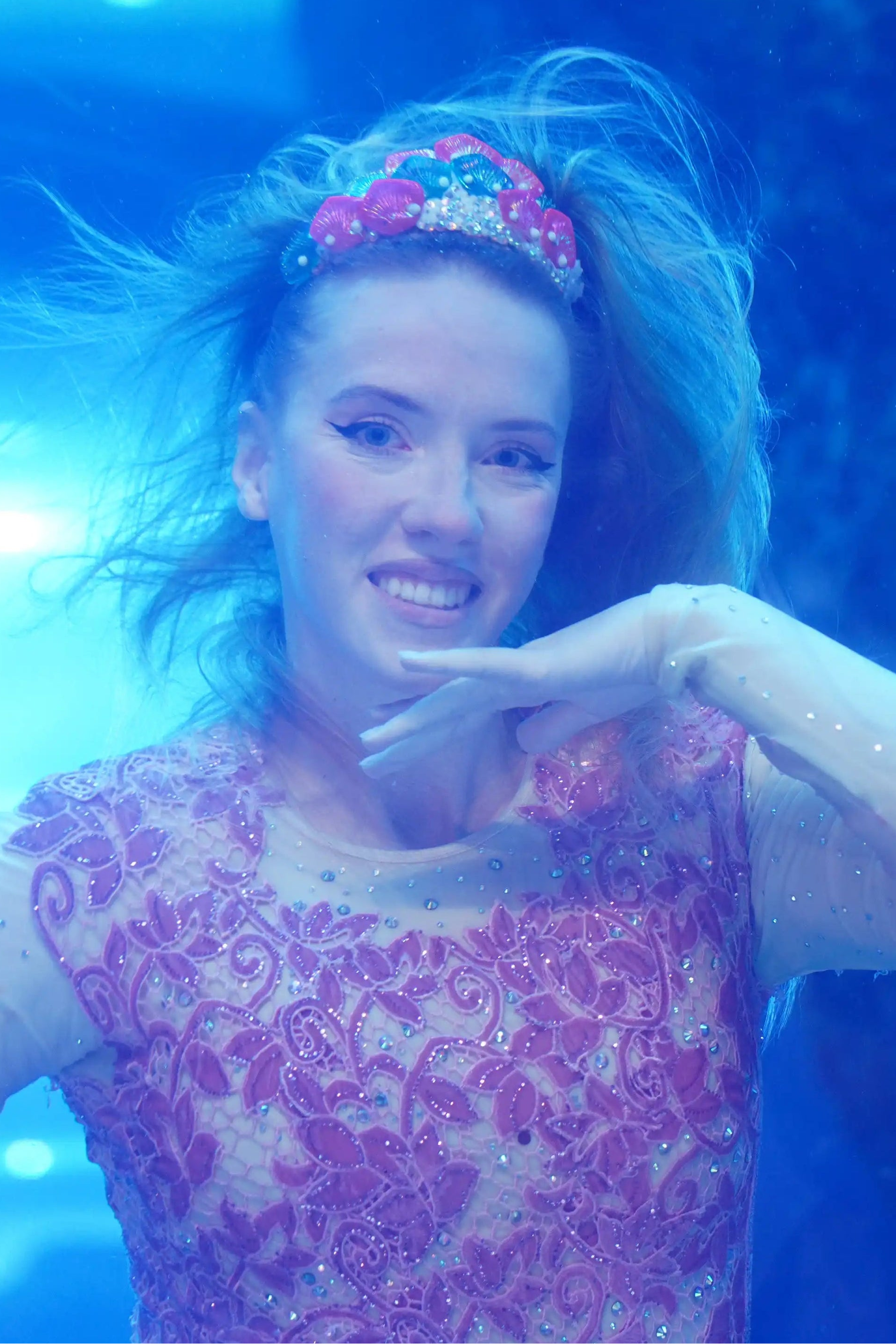 Person underwater wearing a pink and purple outfit with a floral headband.