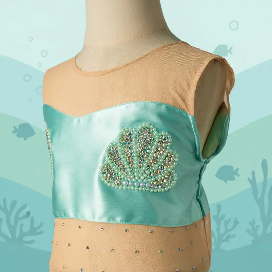 Mannequin wearing a turquoise top with a decorative emblem against an underwater-themed background