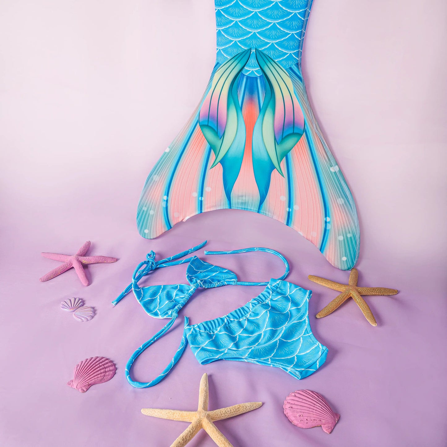 Mermaid tail and bikini set with starfish and shells on a pink background