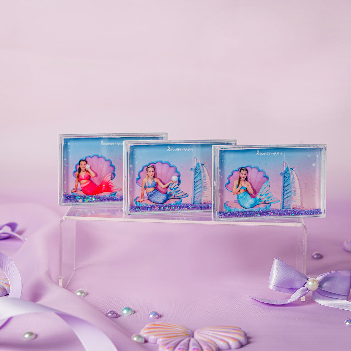 Three decorative frames with mermaid illustrations on a pink background