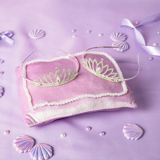 Pink pillow with gold tiaras on a purple background