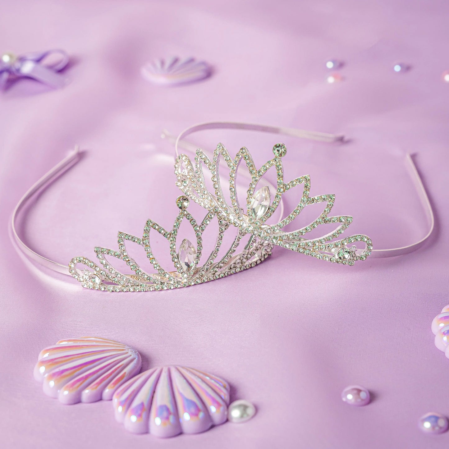 Silver tiara on a purple background with decorative shells and pearls