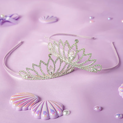 Silver tiara on a purple background with decorative shells and pearls