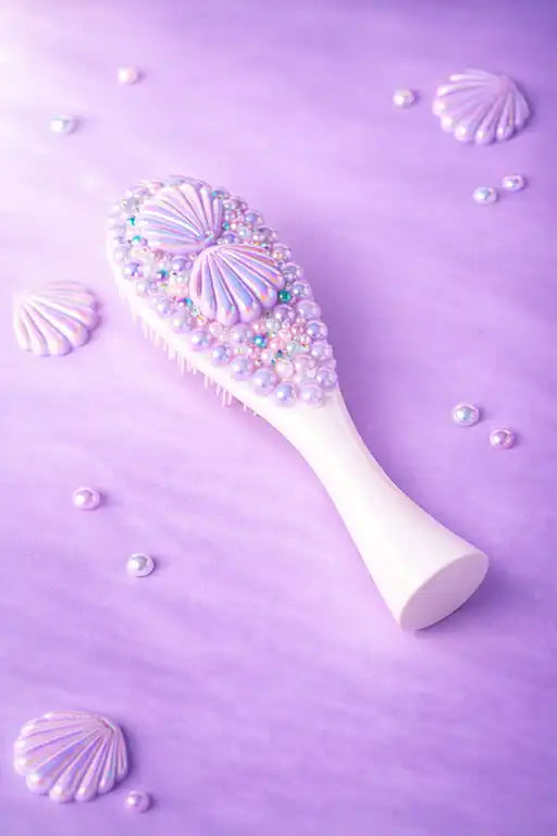 Decorative hairbrush with seashell and pearl details on a purple background