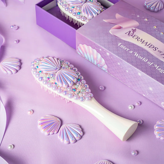 Decorative hairbrush with shell designs on a purple background, featuring the brand 'Mermaids of Magic'.