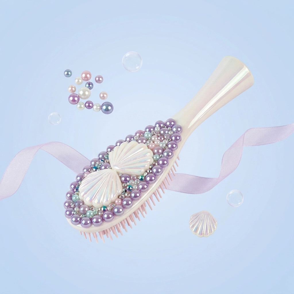 A decorative hairbrush with a pale pink handle and bristles, embellished with white shell motifs, lavender pearls, iridescent beads, and small rhinestones, floating on a light blue background with ribbon and bubble props.