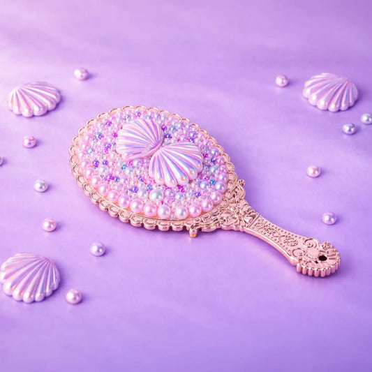 Decorative hand mirror with shell and pearl design on a purple background