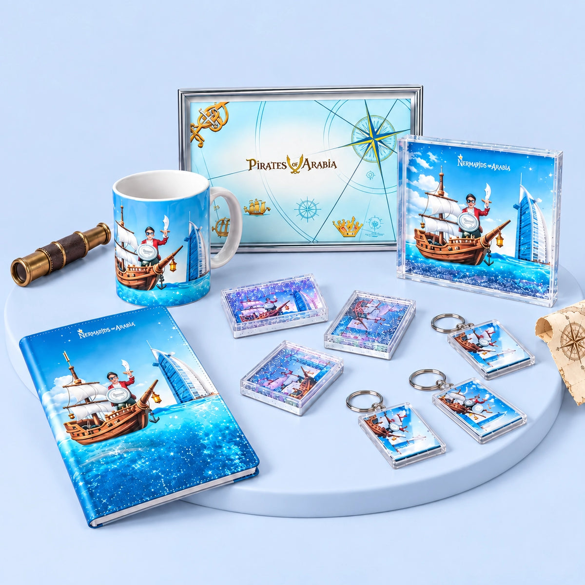 A coordinated Pirates of Caribbean merchandise set arranged on a light blue studio background, including a notebook, mug, framed print, card, keychains, and small accessories, all featuring blue ocean and ship artwork.
