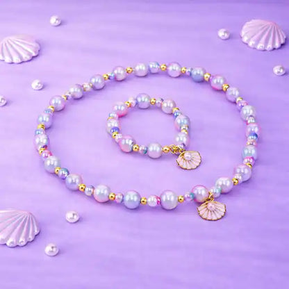 Pearl necklace and bracelet set with shell charms on a purple background