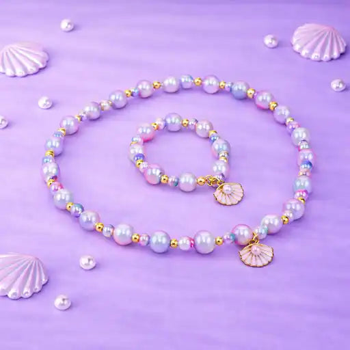 Pearl necklace and bracelet set with shell charms on a purple background