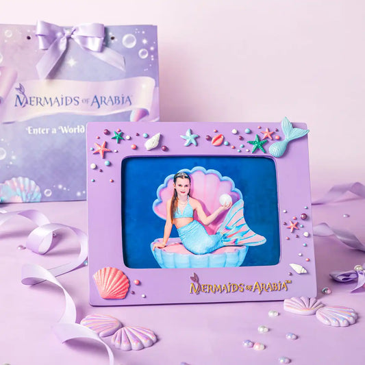 Purple mermaid-themed photo frame with a mermaid toy inside, on a pink background with 'Mermaids of Arabia' branding.