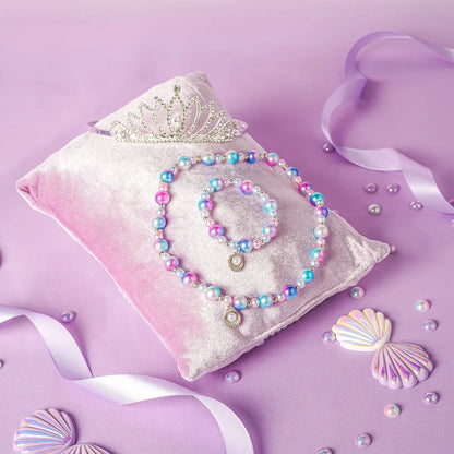 Set of colorful jewelry on a pink pillow with seashells and ribbons on a purple background