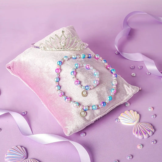 Set of colorful jewelry on a pink pillow with seashells and ribbons on a purple background