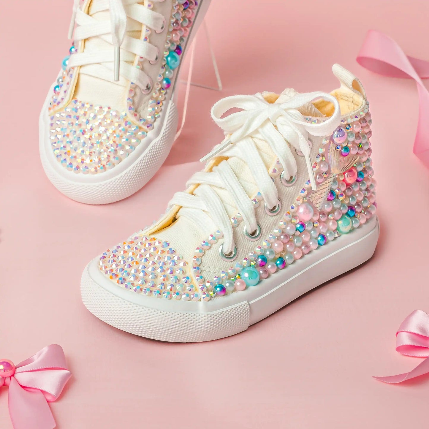 White sneakers with colorful embellishments on a pink background