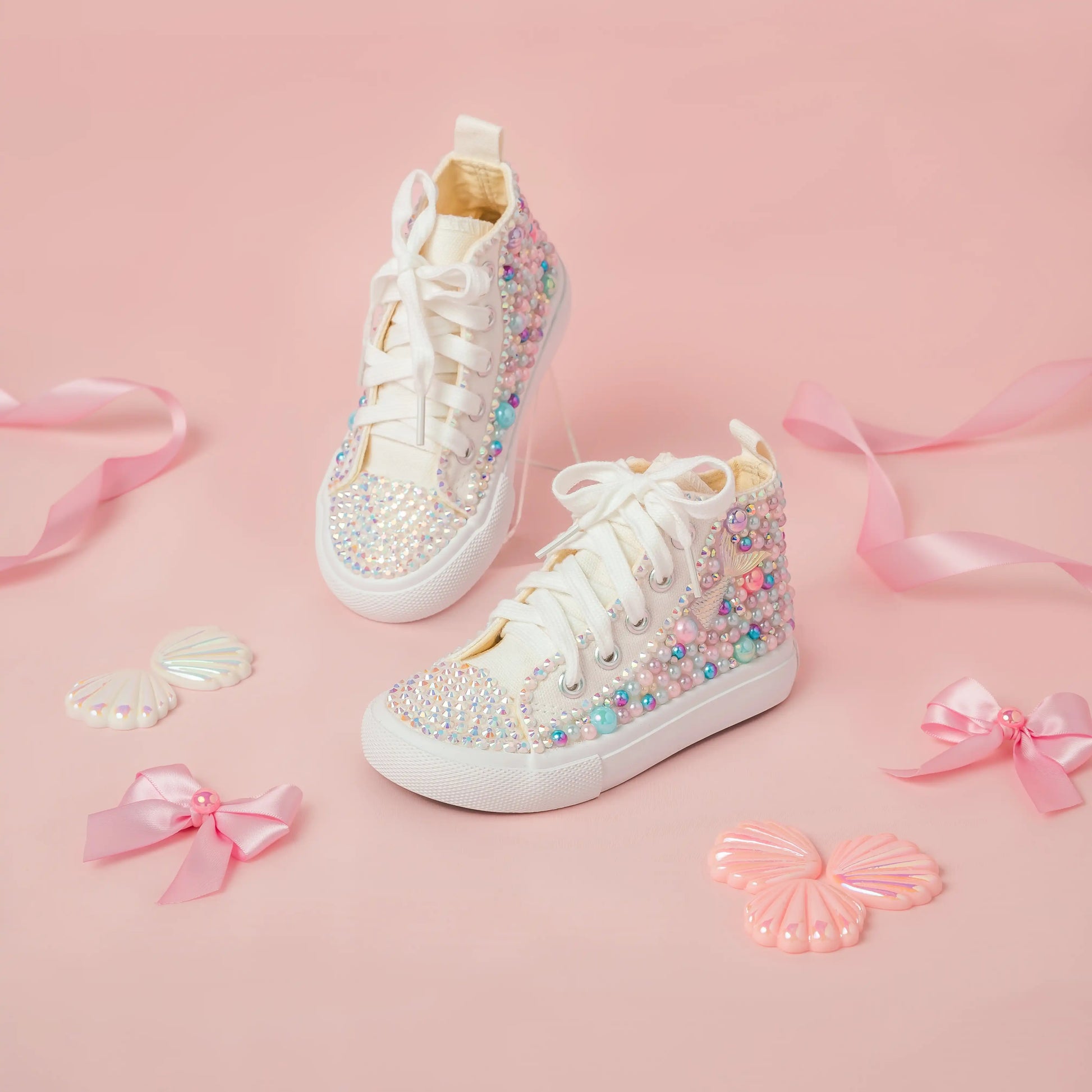 White high-top sneakers with colorful embellishments on a pink background