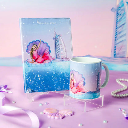 Mermaid-themed notebook and mug set with a castle and seashell design on a pastel background.