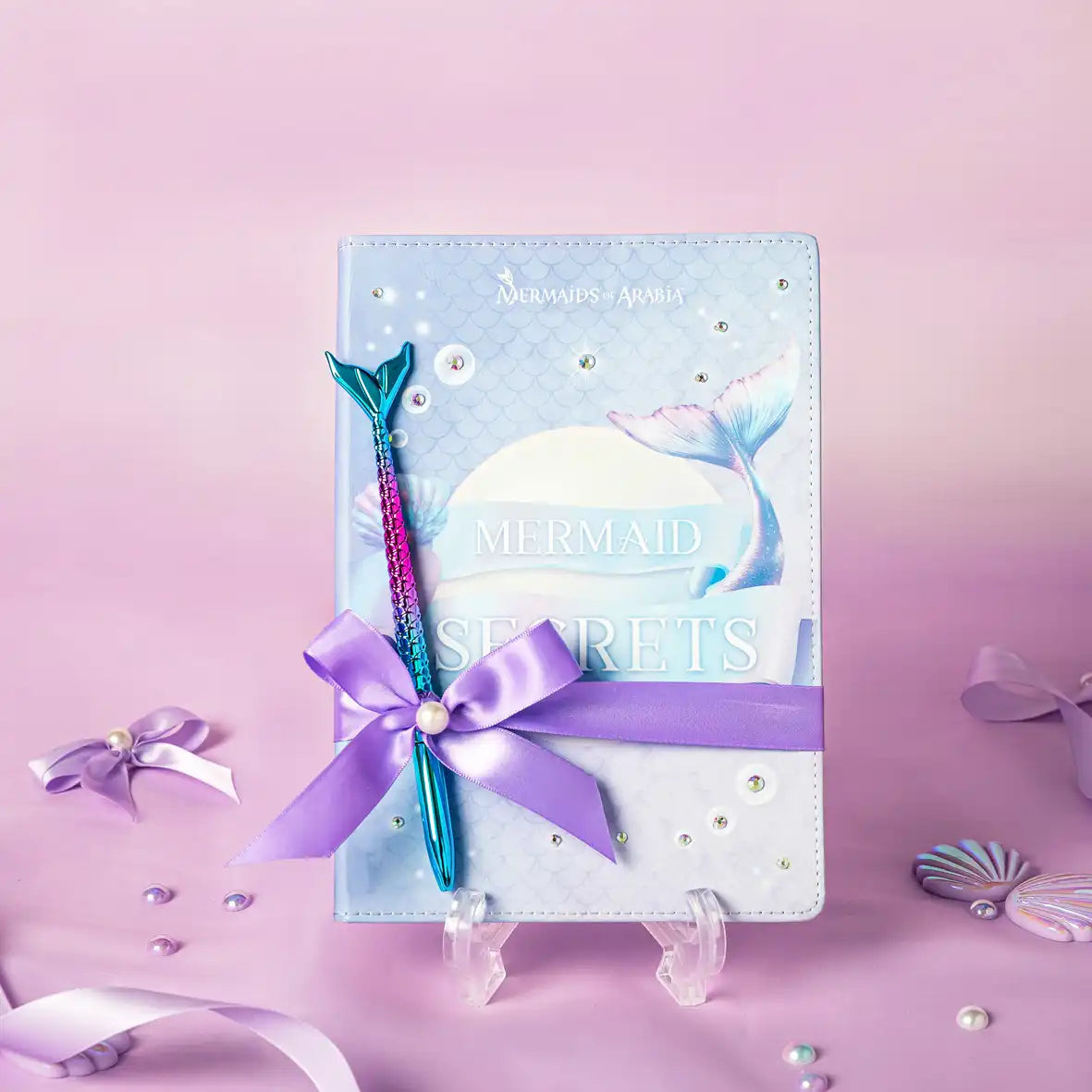 Mermaid-themed notebook with a pen on a pink background