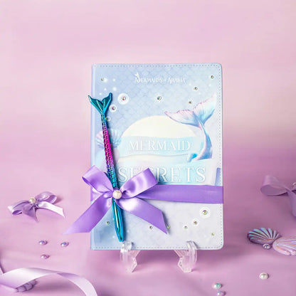 Mermaid-themed notebook with a pen on a pink background