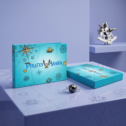 A turquoise pirate-themed jewelry box set with nautical illustrations, shown alongside a ring with a dark pearl on a light blue surface. The packaging features the text 'PIRATES OF ARABIA' and decorative compass, ship, and anchor motifs.