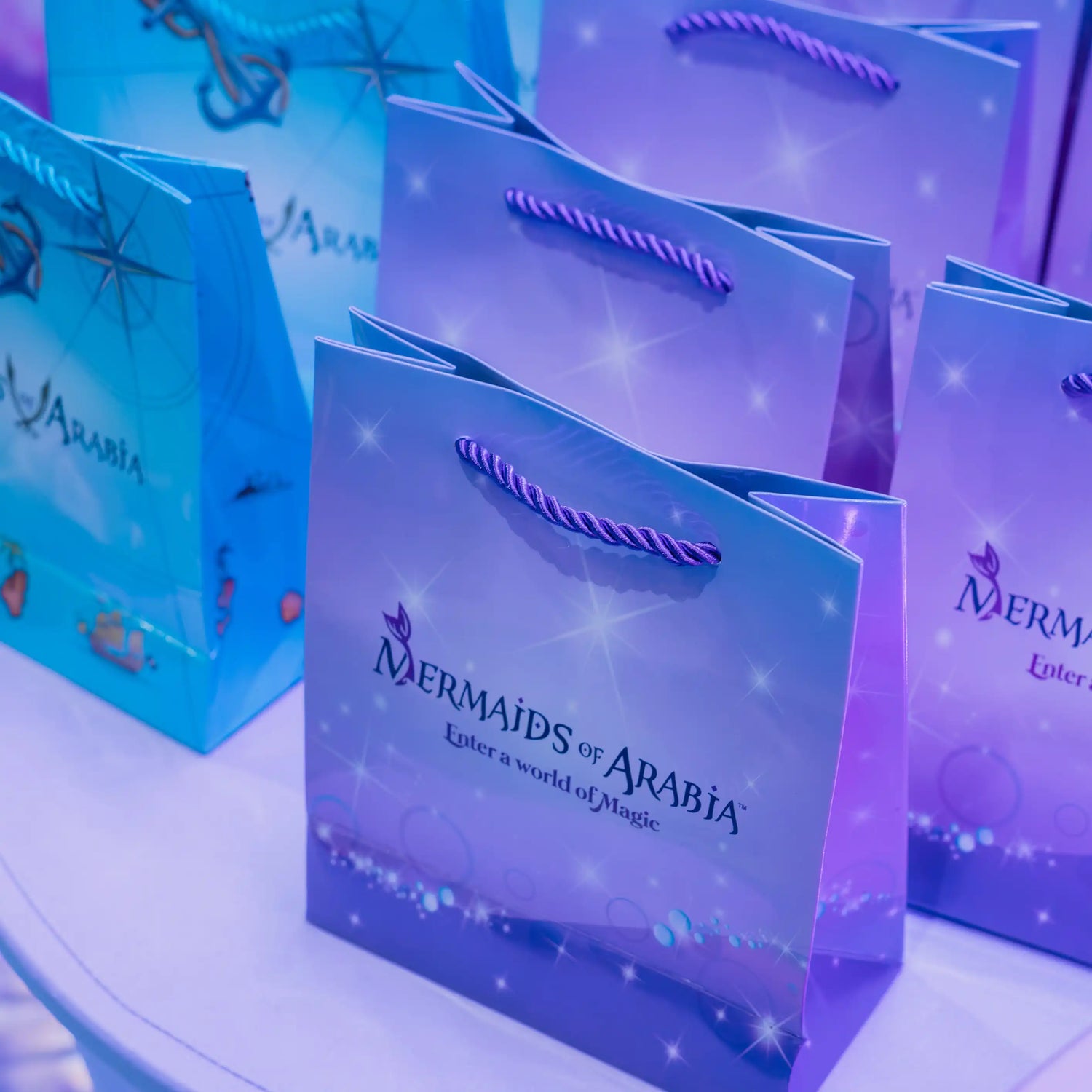 Mermaids of Arabia gift bags with blue and purple design on a white surface
