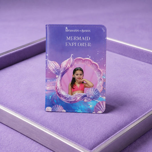 A custom printed children's book or album titled 'Mermaid Explorer' from 'Mermaids of Atlantis', featuring a photo of a young girl in a pink swimsuit on a purple mermaid tail background, displayed on a purple velvet-lined tray.