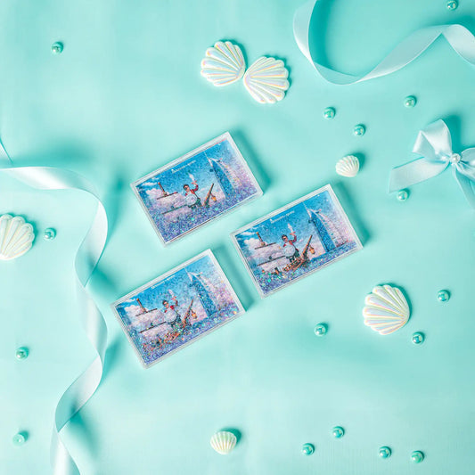 Three decorative cards with mermaid designs on a turquoise background with shells and ribbons.