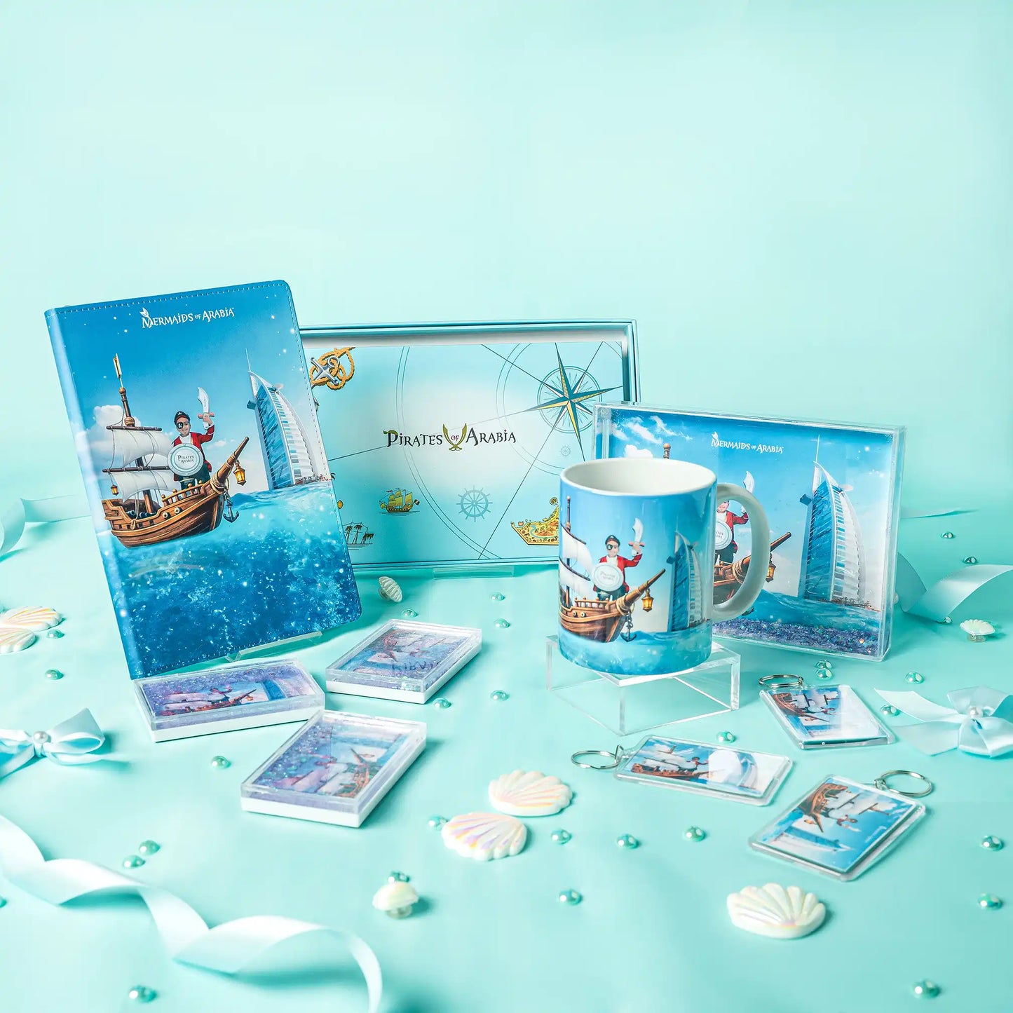 Collection of 'Pirates of the Caribbean' themed merchandise including a mug, cards, and a notebook on a turquoise background.
