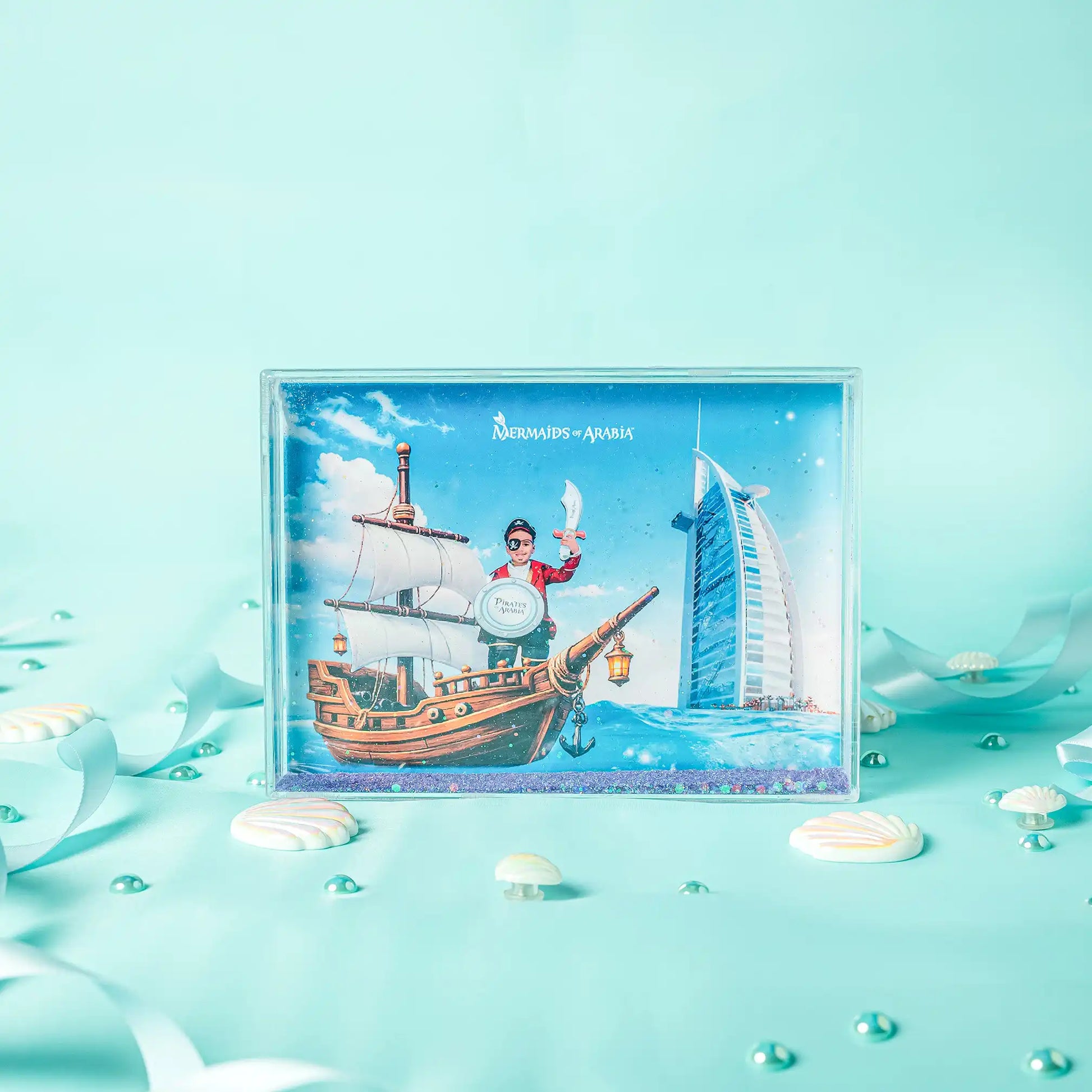 Framed artwork of a pirate ship and building on a light blue background