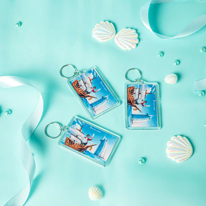 Three keychains with ship designs on a turquoise background with shells and ribbons.