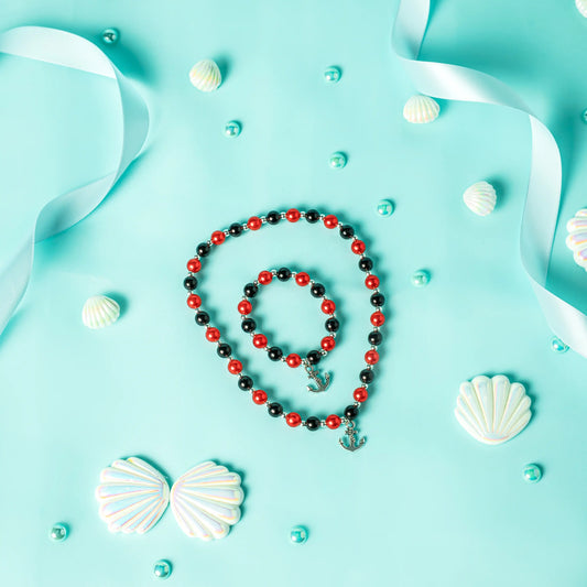 Necklace with red and black beads on a blue background with white ribbons and shells.
