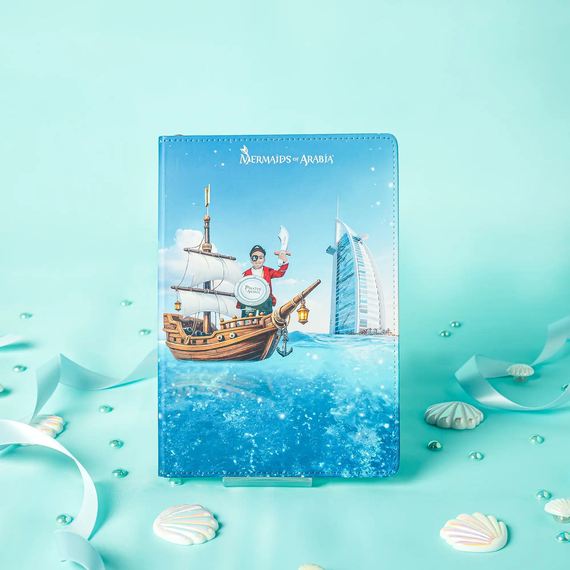 Notebook with a ship and building illustration on a turquoise background