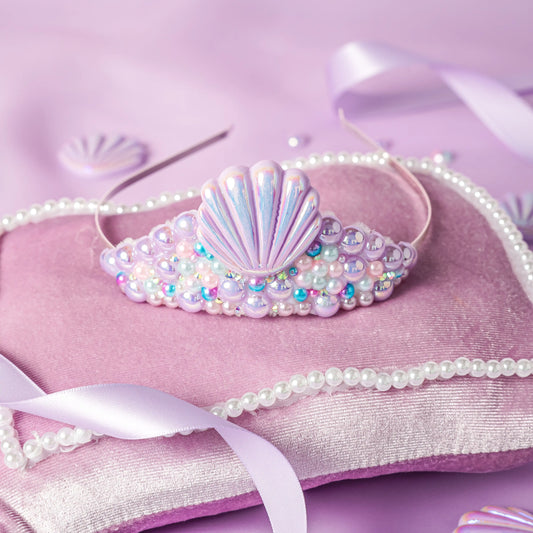 Decorative headband with shell design and beads on a pink background