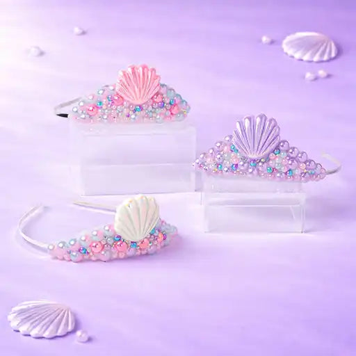 Set of mermaid-themed hair accessories including tiaras and headbands on a purple background with shells and pearls.