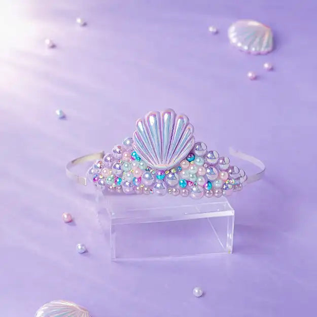 Shell-shaped hair accessory with colorful beads on a purple background
