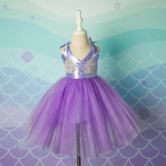 Purple dress on a mannequin against a mermaid scale patterned background