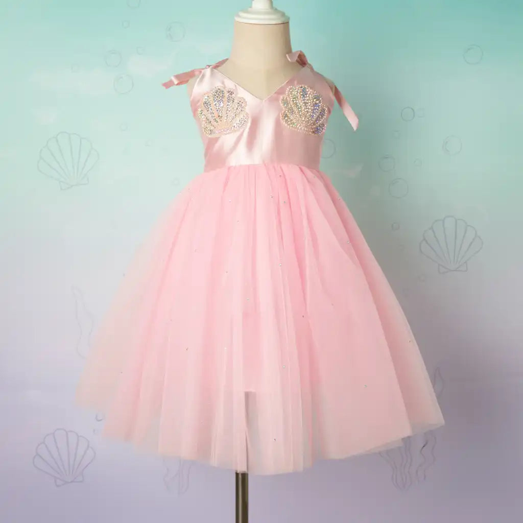 Pink dress with gold embellishments on a mannequin against a light blue background