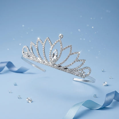 A silver tiara headband adorned with clear rhinestones and a central teardrop crystal, displayed on a light blue background with scattered decorative crystals and ribbons.