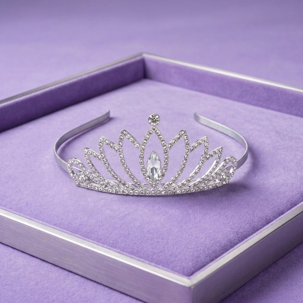 A silver tiara with clear rhinestones and a central marquise-cut crystal, displayed on a purple velvet-lined jewelry box.