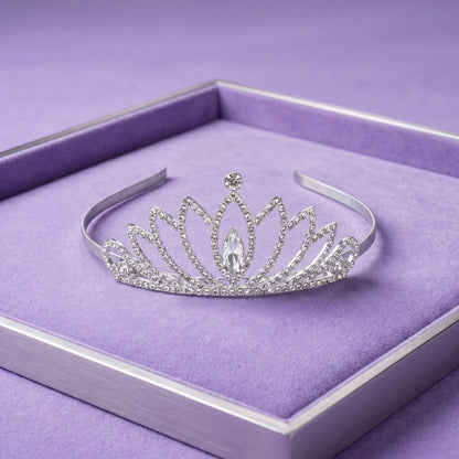 A silver tiara with clear rhinestones and a central marquise-cut crystal, displayed on a purple velvet-lined jewelry box.